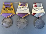 three medals are displayed on a table with a purple ribbon