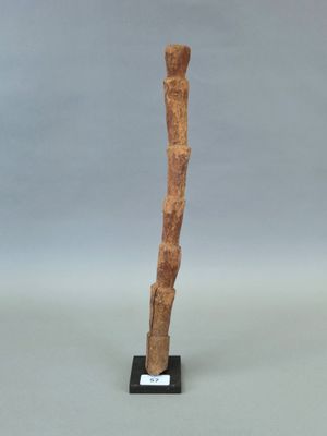 une photo d'une sculpture représentant un bâton en bois posé sur un socle noir