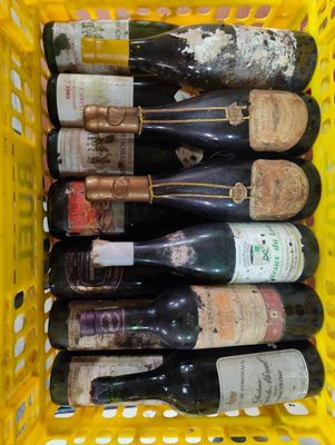 plusieurs bouteilles de vin dans un panier jaune posé sur la table