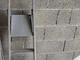 une échelle appuyée contre un mur de briques, avec une chaise posée dessus