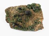 des cristaux verts et noirs posés sur un rocher, sur une surface blanche