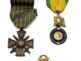three medals and a cross are on a white surface