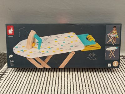 une boîte ouverte contenant une planche à repasser jouet posée sur une table