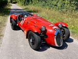 une voiture de course rouge garée sur le bord de la route