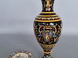 a black and gold vase next to a plate on a table