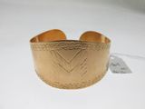 un gros plan d'un bracelet manchette en or orné d'un motif