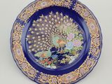 a blue plate with a peacock and flowers on it