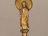 statue en or représentant une personne tenant un éventail, posée sur une table en verre