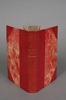 an open book with a red cover sitting on top of a table