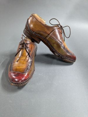 two pairs of brown and red shoes sitting on top of a gray surface