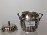 a silver pot and a silver lid on a table