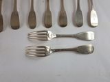 several forks and spoons are lined up on a white surface
