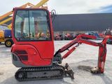 a small red excavator that is parked in a lot