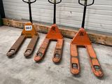 Trois chariots élévateurs orange sont alignés devant la porte d'un garage