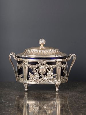 un plat à couvercle ancien, en argent et en verre bleu, posé sur une table