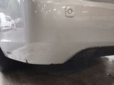 the rear end of a white car with scratches on the bumper