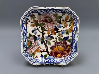 un petit plat carré orné de fleurs et d'oiseaux