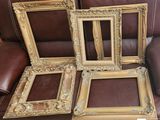 Plusieurs cadres anciens sont posés sur un canapé dans une pièce