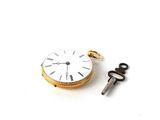 une montre de poche en or et une clé posées sur une surface blanche