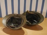 two helmets sitting on a table with a striped wall in the background