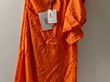 une robe orange suspendue à un cintre accroché au mur