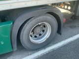 a green semi truck with a flat tire parked in a parking lot