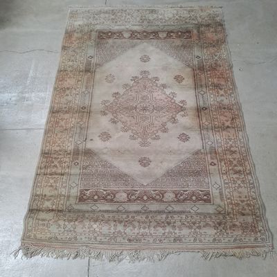 un tapis posé au sol au milieu d'une pièce, avec une chaise à l'arrière-plan