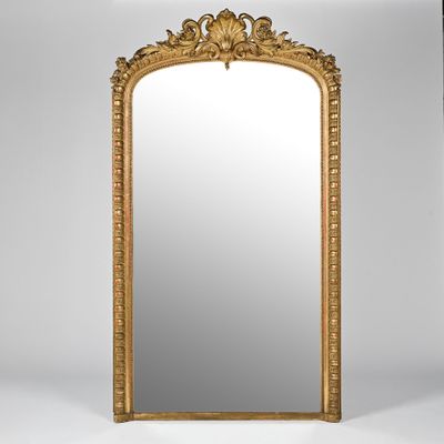 un grand miroir à cadre doré orné d'un motif décoratif