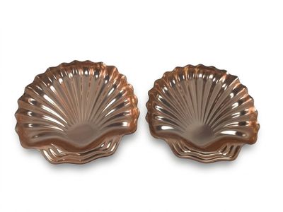deux plats en cuivre en forme de coquillage sur fond blanc
