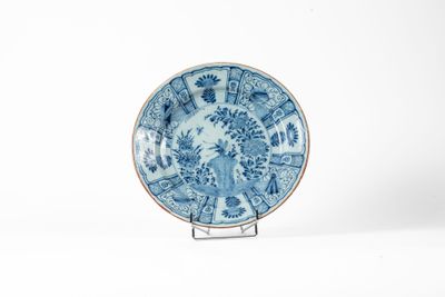assiette bleue et blanche posée sur un support, sur fond blanc