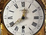 a gold clock with roman numerals on the face
