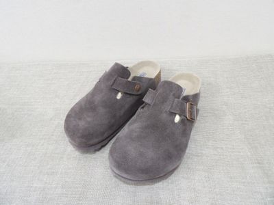 grey sued slippers with buckles on a white surface