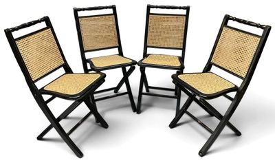 quatre chaises pliantes noires avec des assises en osier sur fond blanc