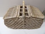 a wicker basket with a handle on a white table
