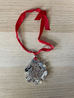 a close up of a silver ornament on a red ribbon