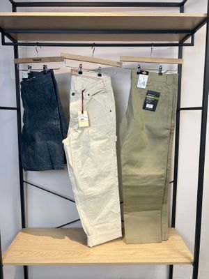 deux pantalons pour homme suspendus à un portant dans un magasin de vêtements