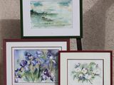 trois photos encadrées représentant des fleurs, posées sur une étagère contre un mur