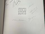 an open book sitting on top of a wooden table covered in autographs