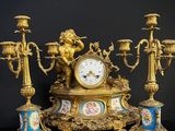 a gold clock sitting on top of a table with candles