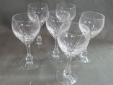 six empty wine glasses sitting on a table with a gray background