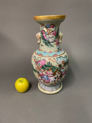a vase with a dragon on it next to an apple