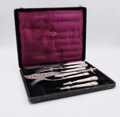 un service d'argenterie ancienne présenté dans un coffret noir doublé de velours violet