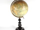 un globe antique posé sur un socle noir, sur fond blanc