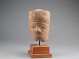 sculpture représentant une tête d'homme, posée sur un socle en bois