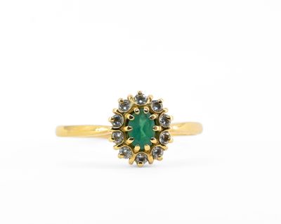 une bague en or sertie d'une pierre verte entourée de petits diamants blancs