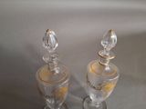 two clear glass jars with gold designs on them