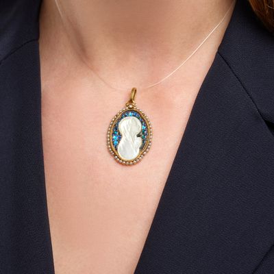 a close up of a woman wearing a necklace with a blue and white cameo