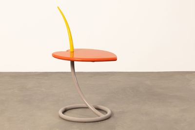 an orange side table with a curved metal base and a yellow flower on top