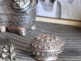 two silver figurines sitting on top of a wooden table