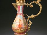 un vase doré et rouge posé sur un socle, sur fond noir